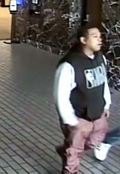 Photo of fraud suspect wearing a black and white long sleeve NBA shirt with light maroon pants. 